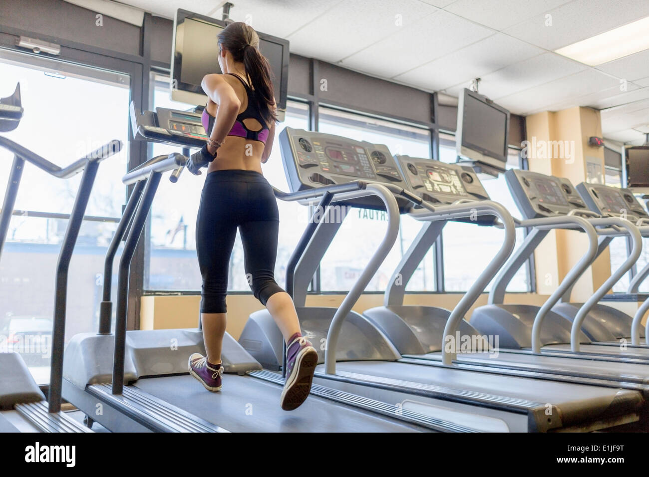 Mid adult woman running on treadmill in gym Stock Photo