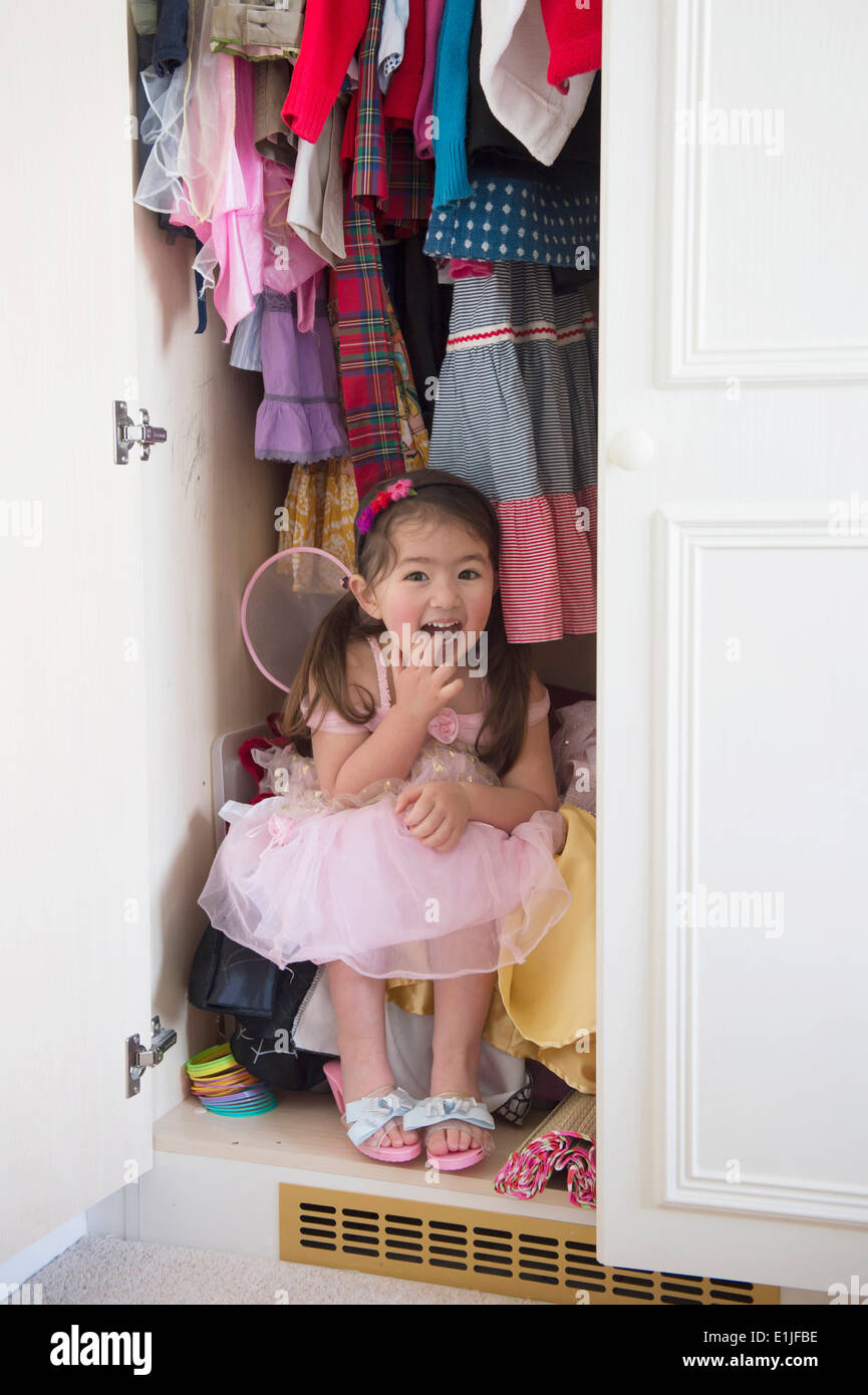 Girl in princess costume hiding in cupboard Stock Photo