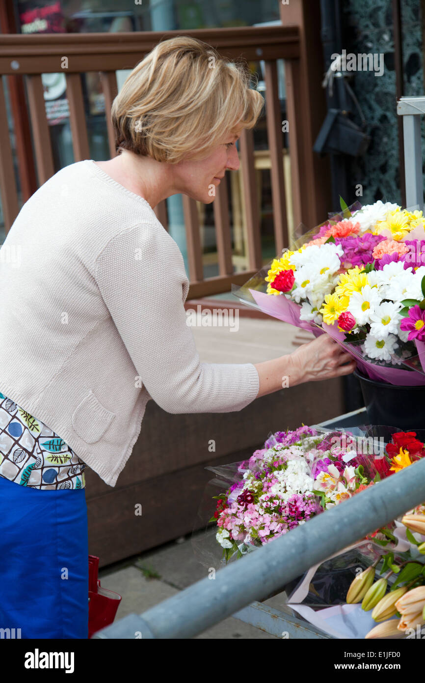 Woman Choosing Bunch of Flowers outside Convenience Store Stock Photo