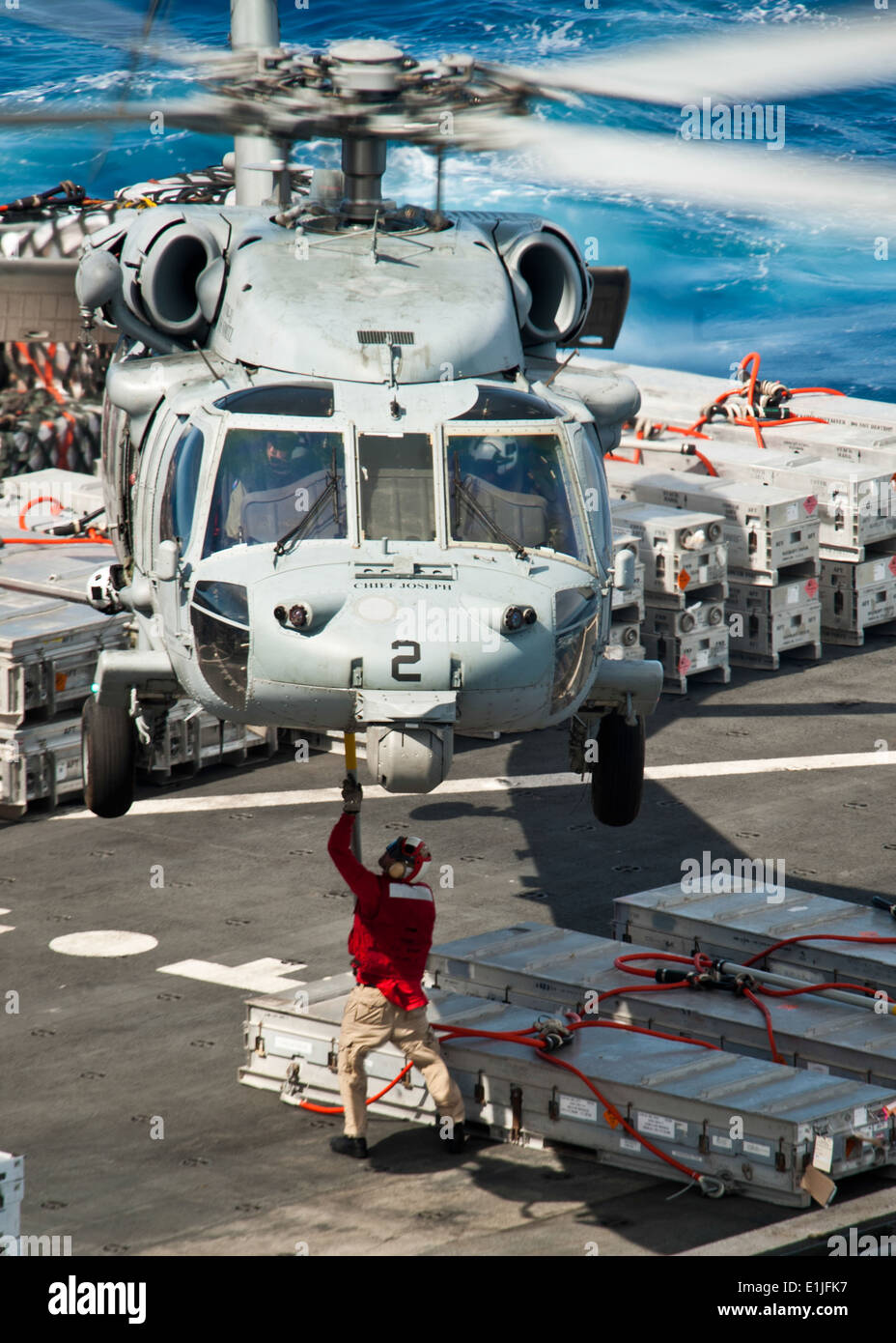 A crewmember aboard the dry cargo and ammunition ship USNS Richard E. Byrd (T-AKE 4) attaches a cargo hook to an MH-60S Seahawk Stock Photo