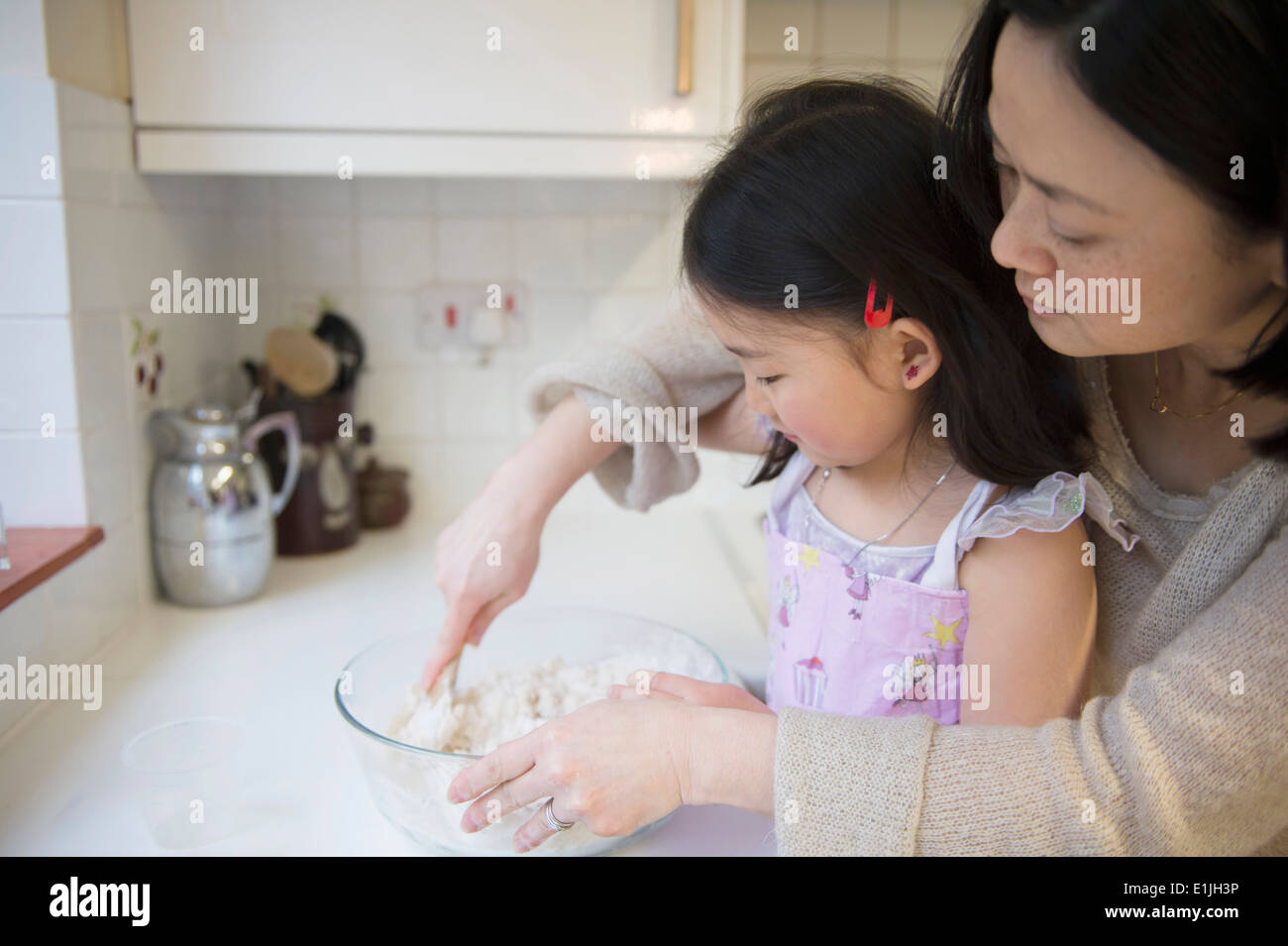 Mother and daughter in kitchen, mixing ingredients in bowl Stock Photo