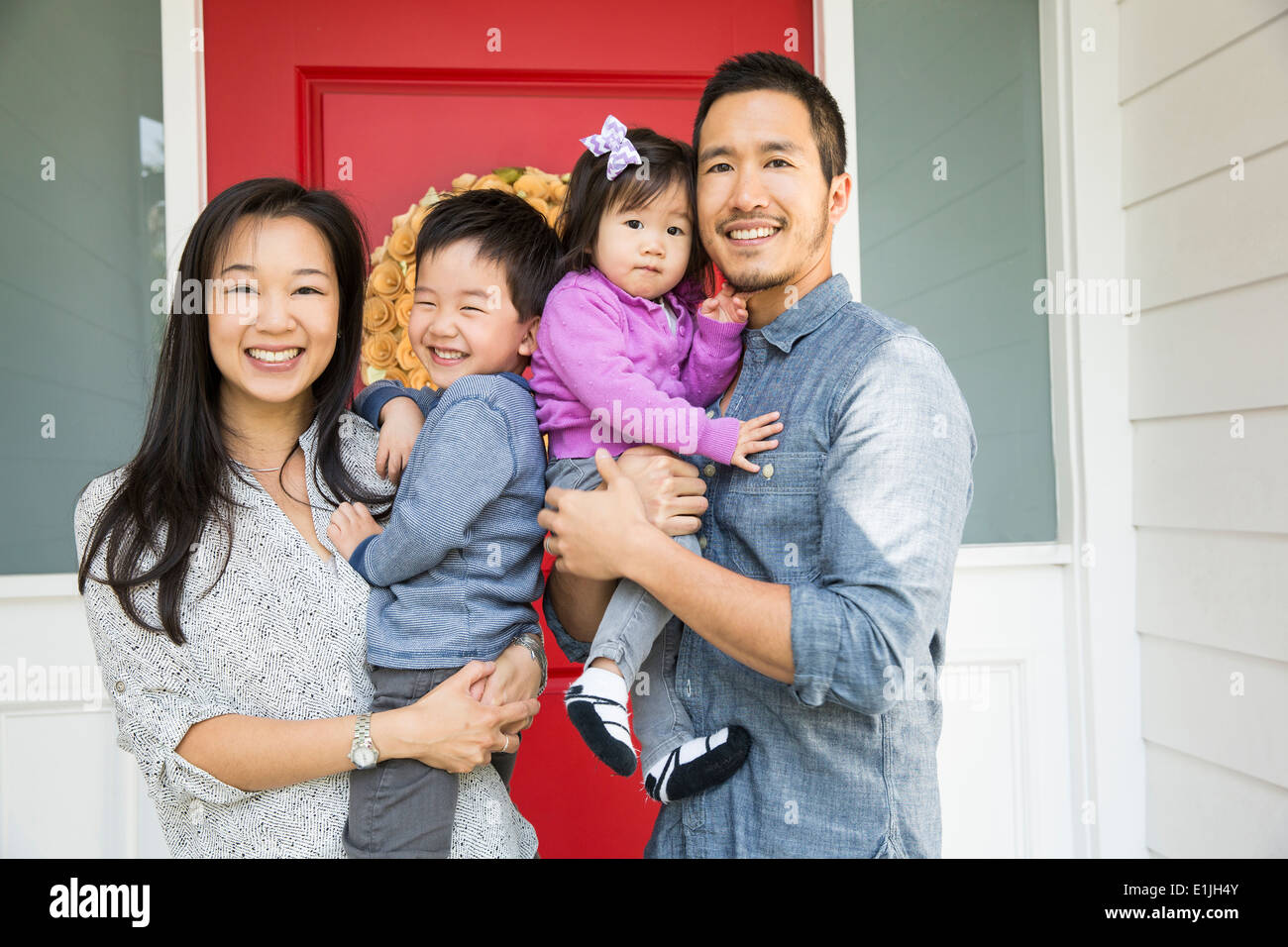 Portrait of mid adult couple and two young children on porch Stock Photo