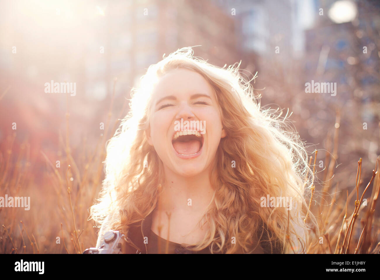 Young woman in long grass with open mouth Stock Photo