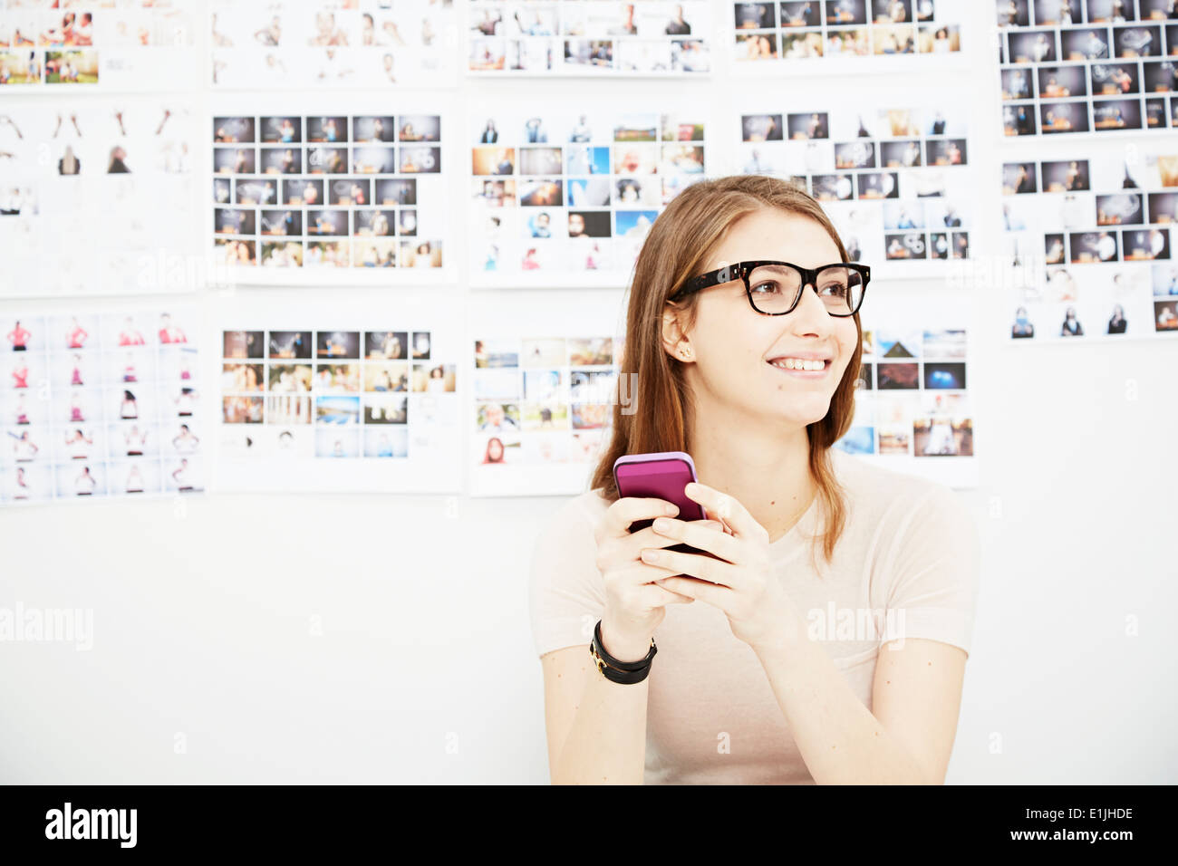 Young woman using cell phone in creative studio Stock Photo