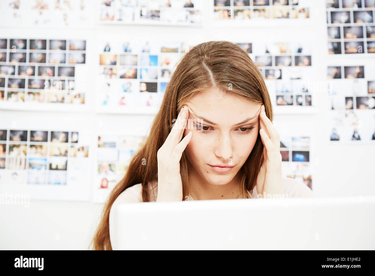 Young woman using computer rubbing head Stock Photo