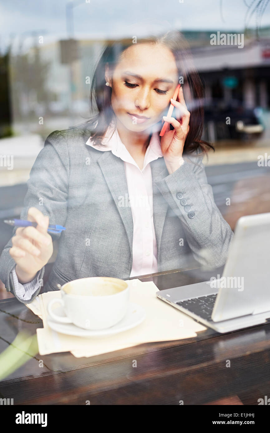 Young female businesswoman taking on smartphone in cafe Stock Photo