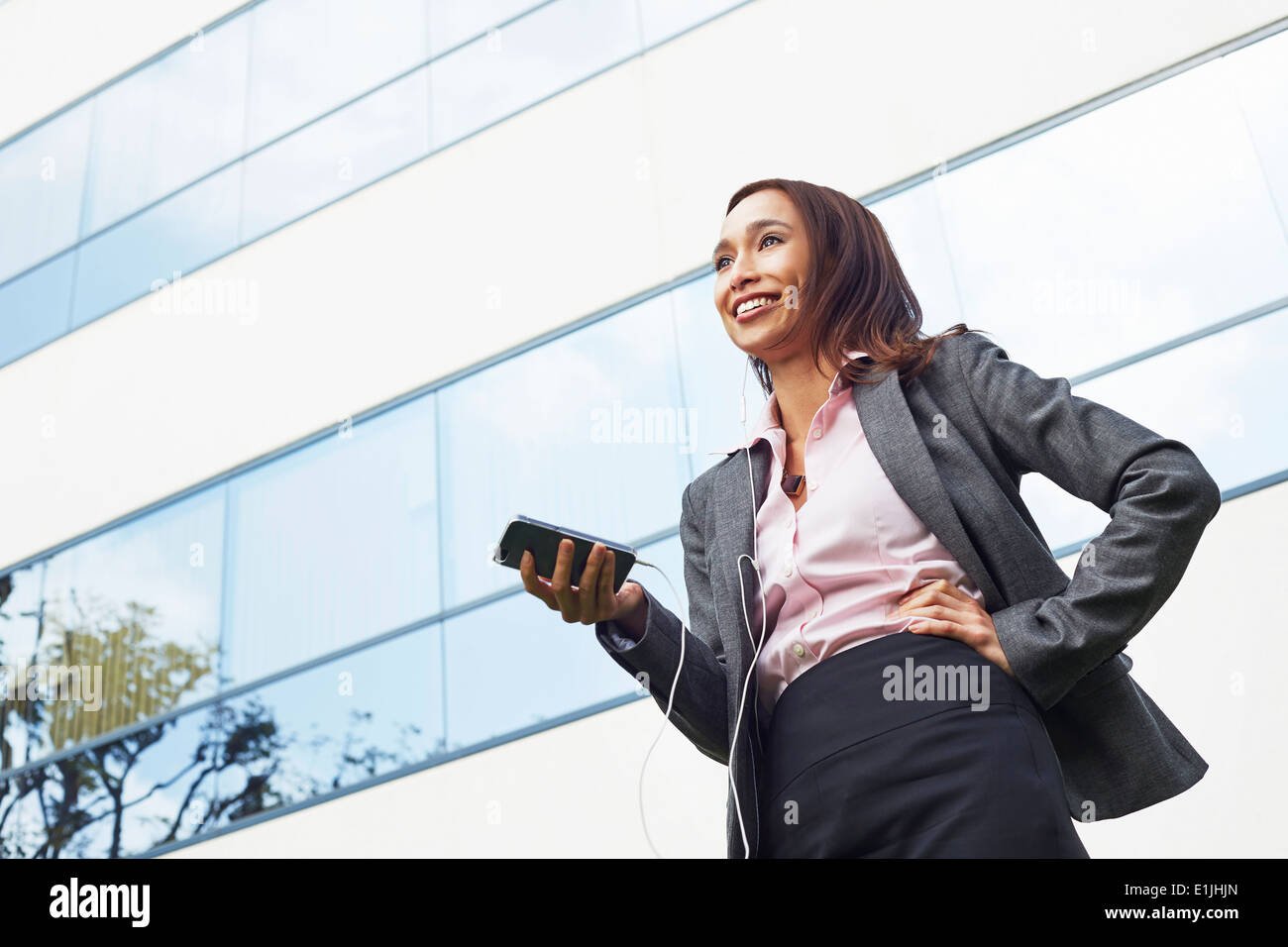 Young female businesswoman using smartphone outside office Stock Photo