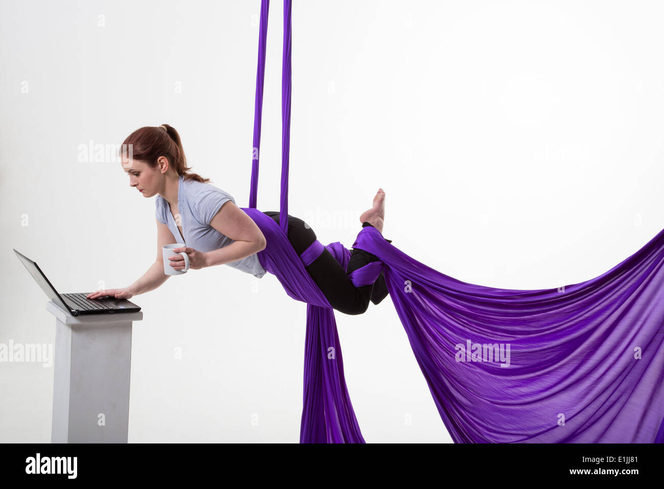 woman hanging in the air with a laptop computer and mug of coffee Stock