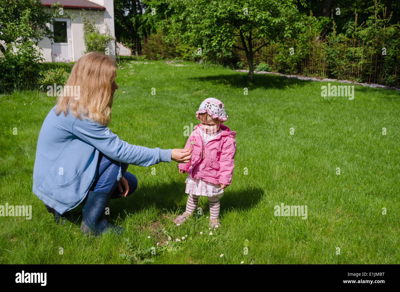 mother sits in the meadow daughter gather the small white daisies and give mom Stock Photo