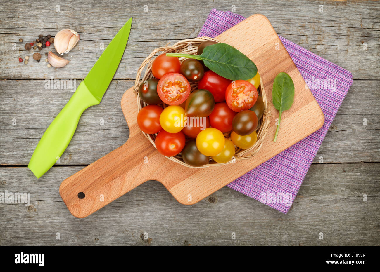 Colorful cherry tomatoes with spices and knife on cutting board over ...