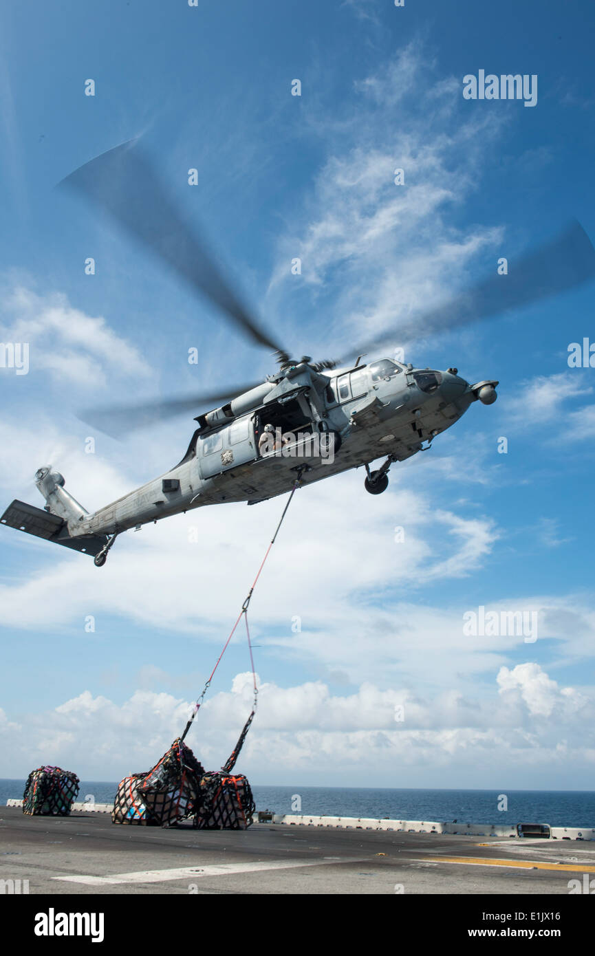 A U.S. Navy MH-60S Seahawk helicopter assigned to Helicopter Sea Combat Squadron (HSC) 21 delivers cargo to the amphibious assa Stock Photo