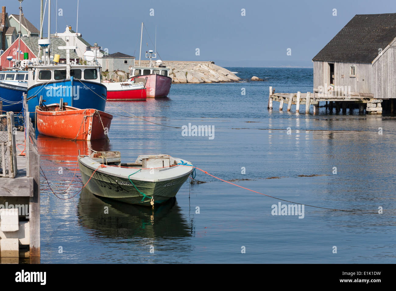 Peggy's Cove Harbour. A tranquil scene of the small harbour at Peggys Cove. Miss Peggy's Cove a blue fishing boat is tied up. Stock Photo