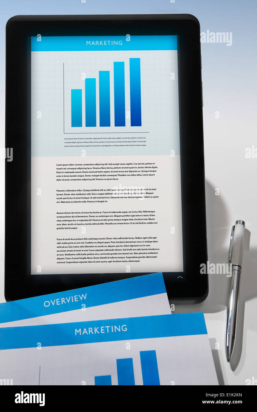 Marketing proposal on a tablet screen with printed documents and pen. Stock Photo