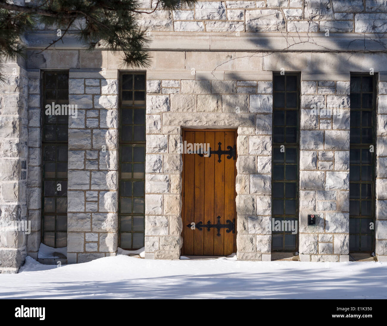 Back Entrance to a stone building. A small wooden door at the back of a limestone clad building on the Queen's University campus Stock Photo