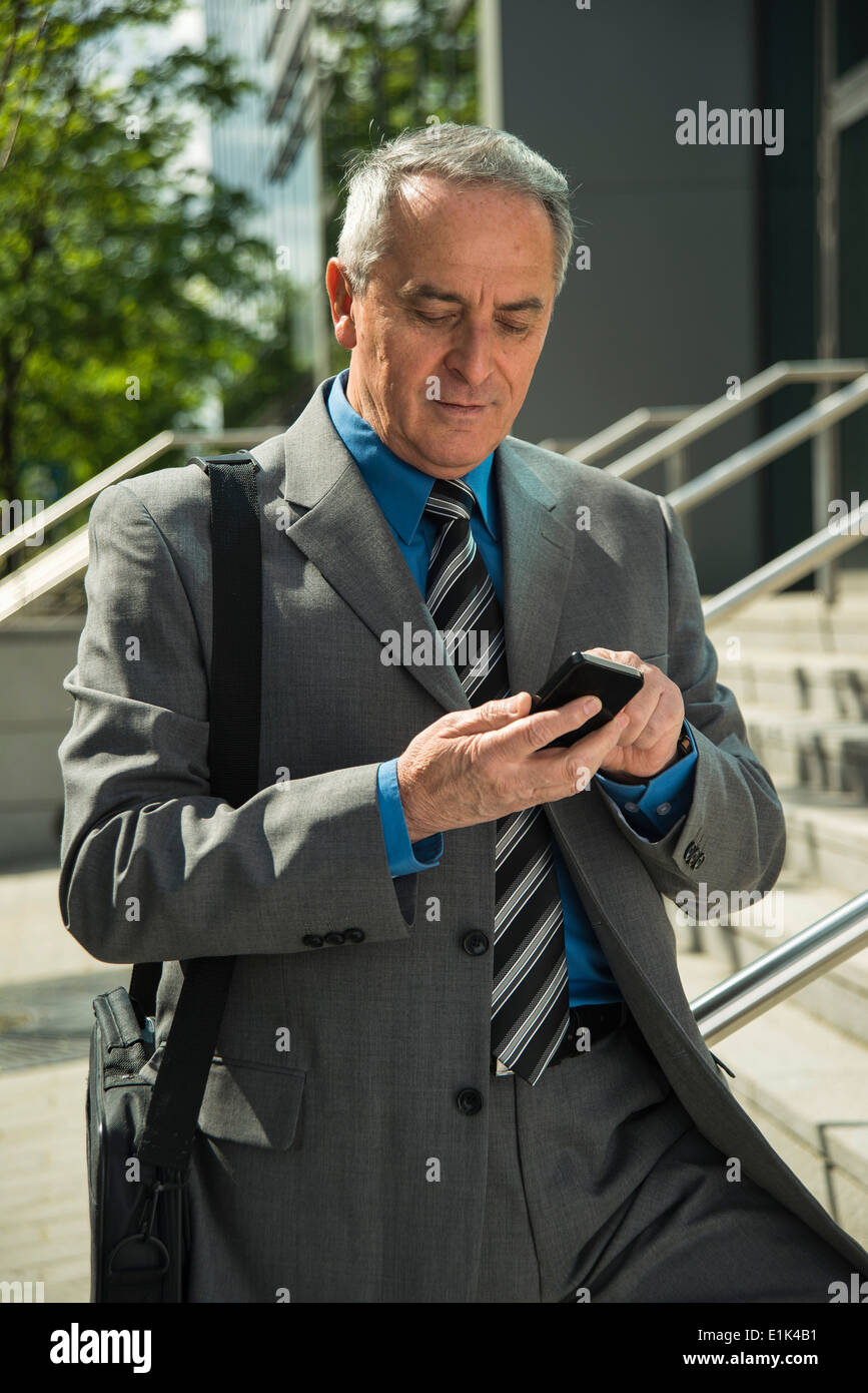 Senior businessman using cell phone outdoors Stock Photo - Alamy