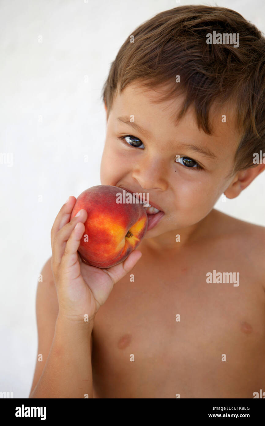Young boy eating a peach Stock Photo Alamy