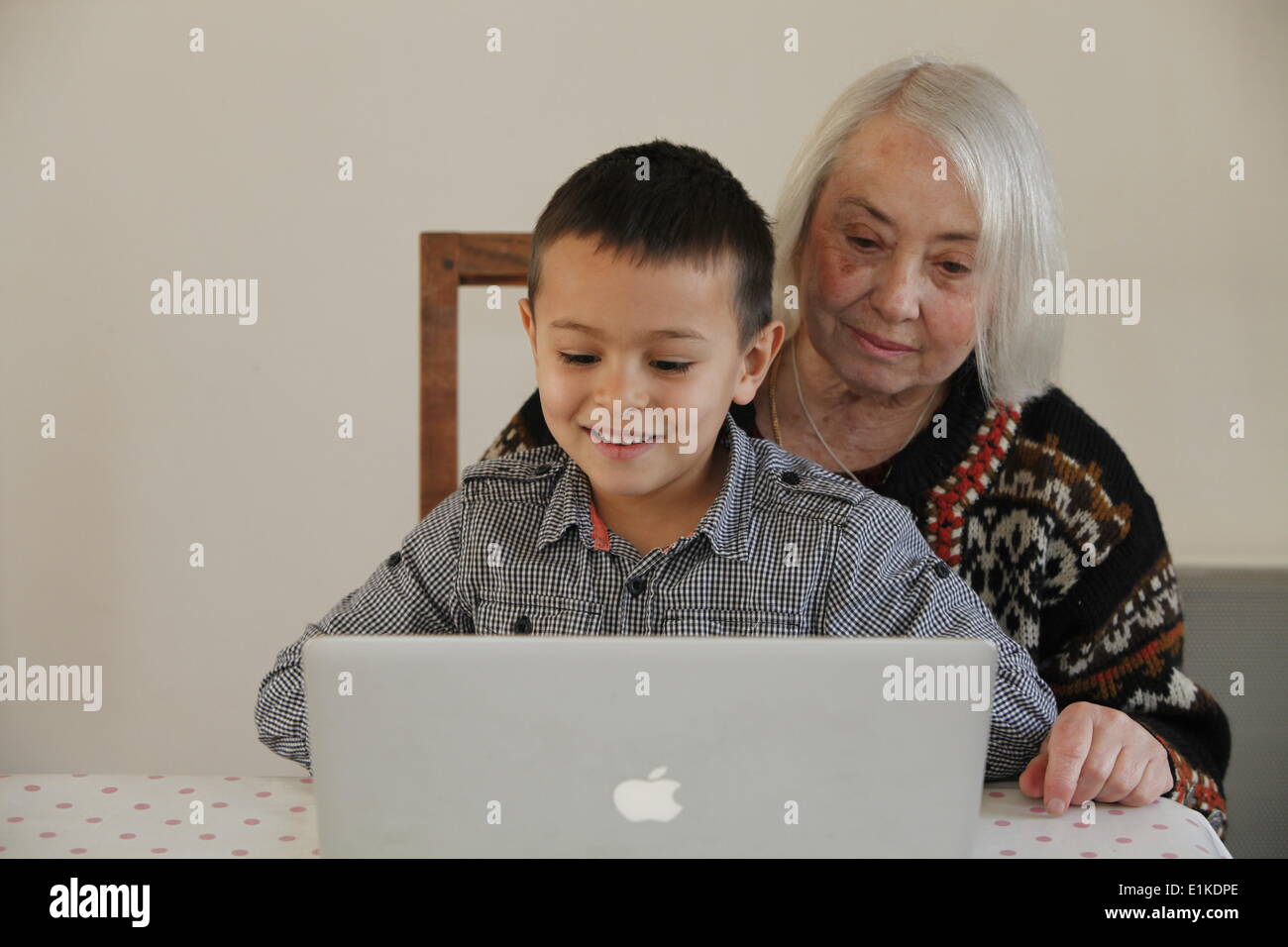 6-year-old boy looking at a laptop with his grandmother Stock Photo