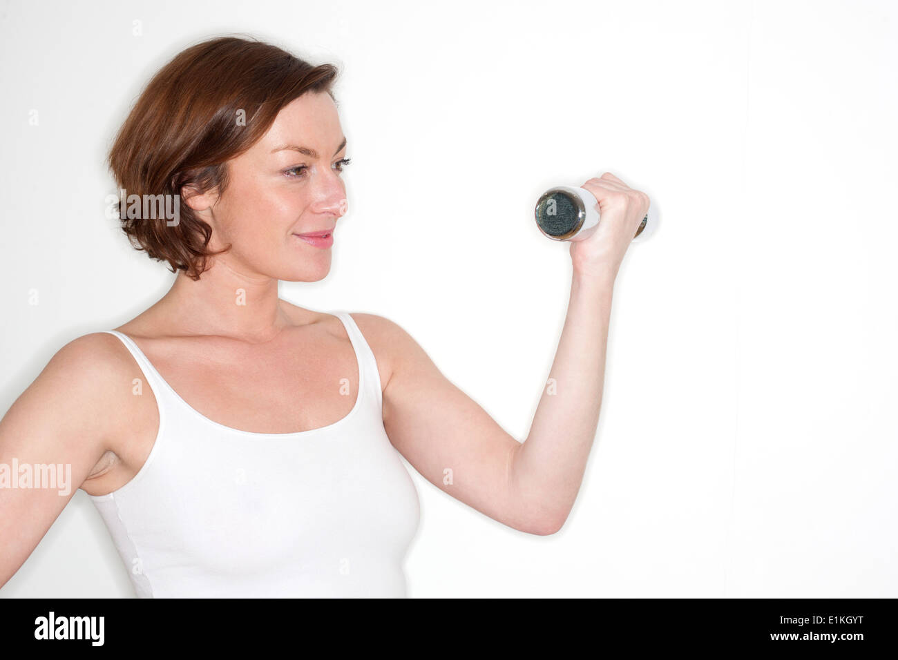 MODEL RELEASED Woman using hand weight studio shot. Stock Photo