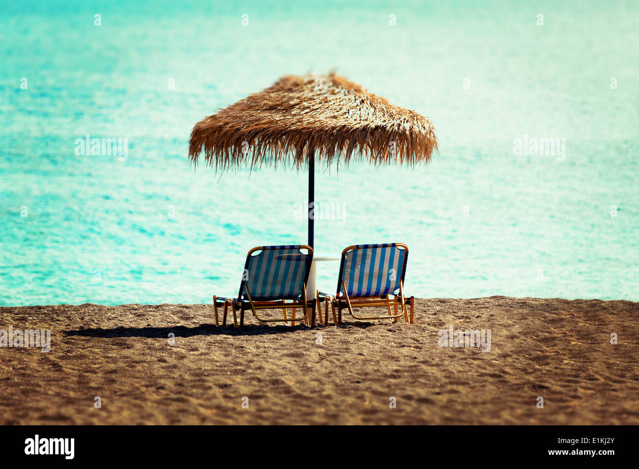 Sunloungers and parasol on an empty beach. Stock Photo