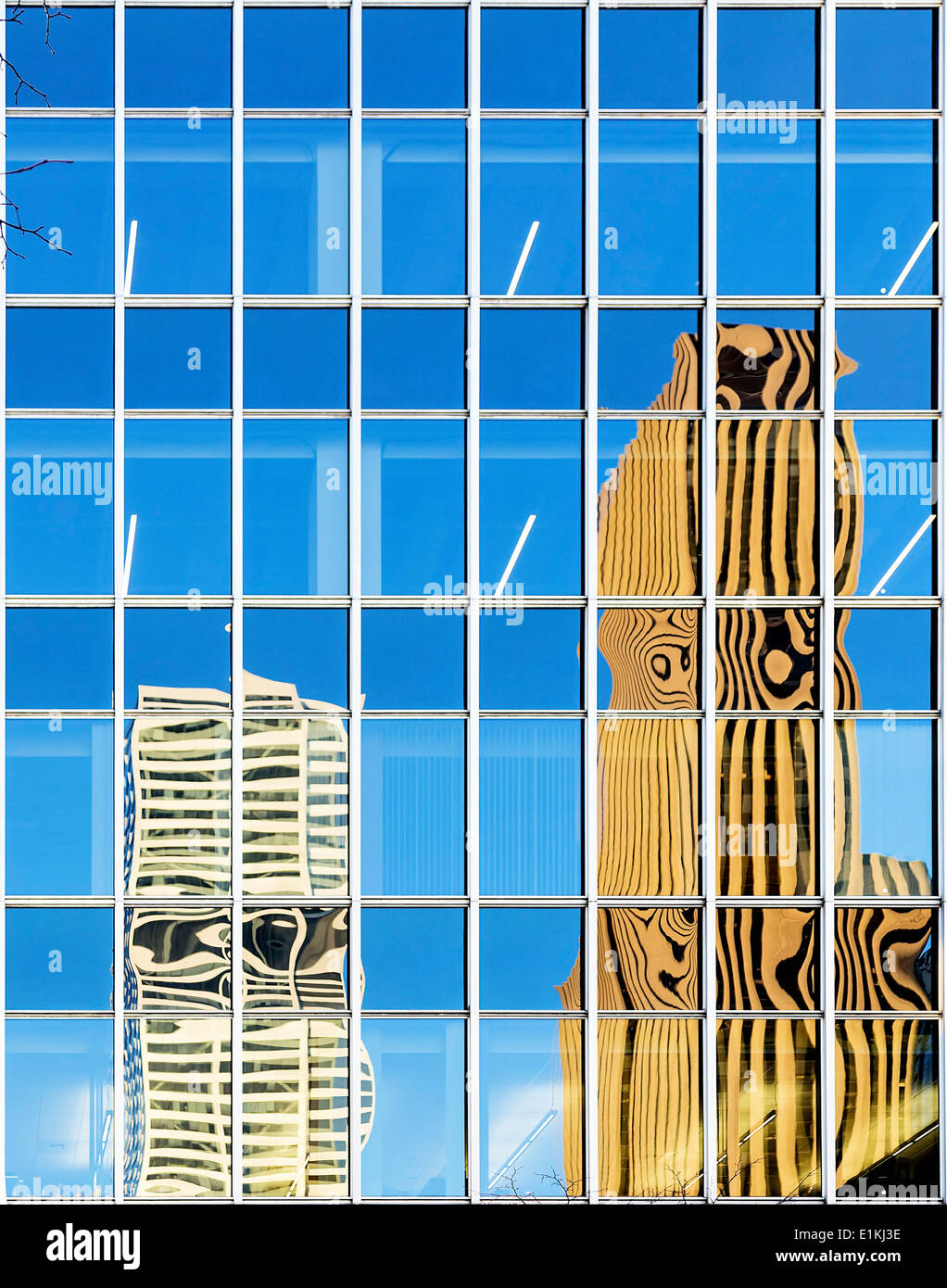 Modern buildings reflected in the glass exterior of an office building. Stock Photo