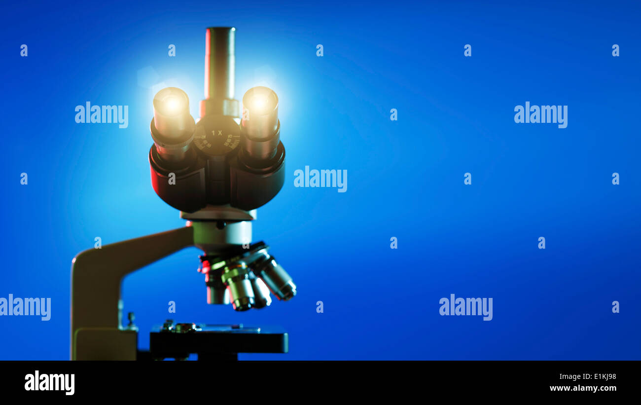 Microscope against a blue background Stock Photo - Alamy