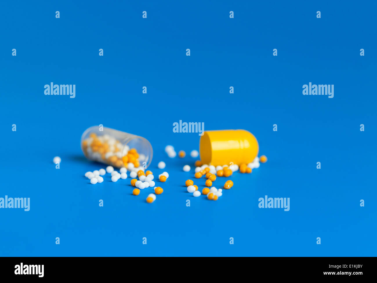 Medicine capsule broken in half with contents spilling out. Stock Photo