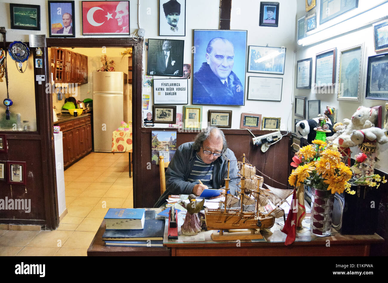 Hotel host on the reception, surrounded by Ataturk portraits, press cuttings, photos and pictures, Lefka, Northern Cyprus Stock Photo