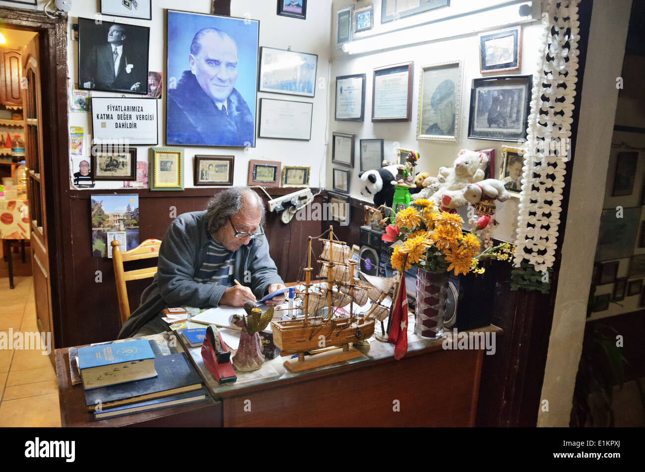 Hotel host on the reception, surrounded by Ataturk portraits, press cuttings, photos and pictures, Lefka, Northern Cyprus Stock Photo