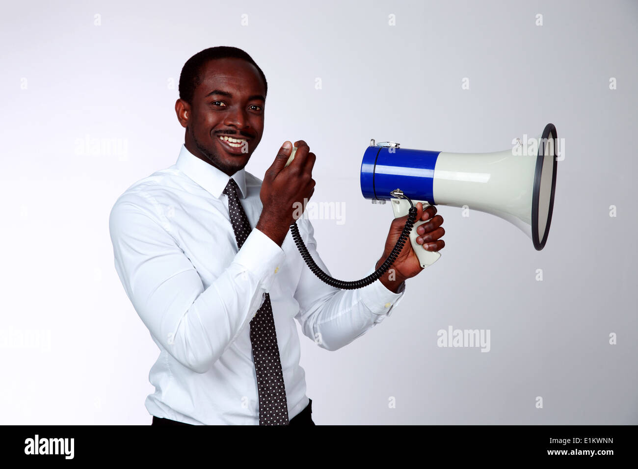 African man shouting through a megaphone on gray background Stock Photo