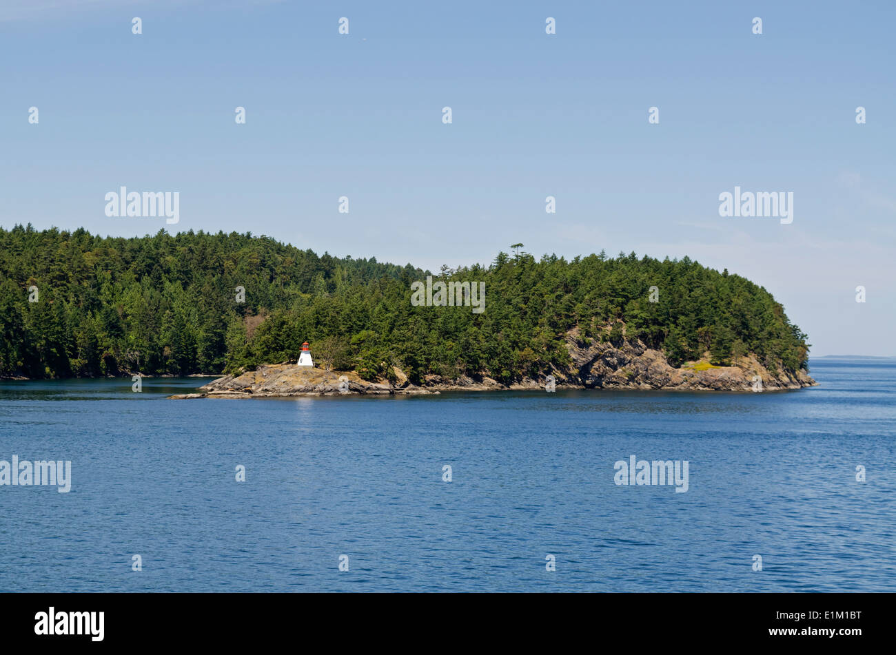 Lighthouse on one of the Southern Gulf Islands.  Forest and rocky shore.  British Columbia, CA Stock Photo