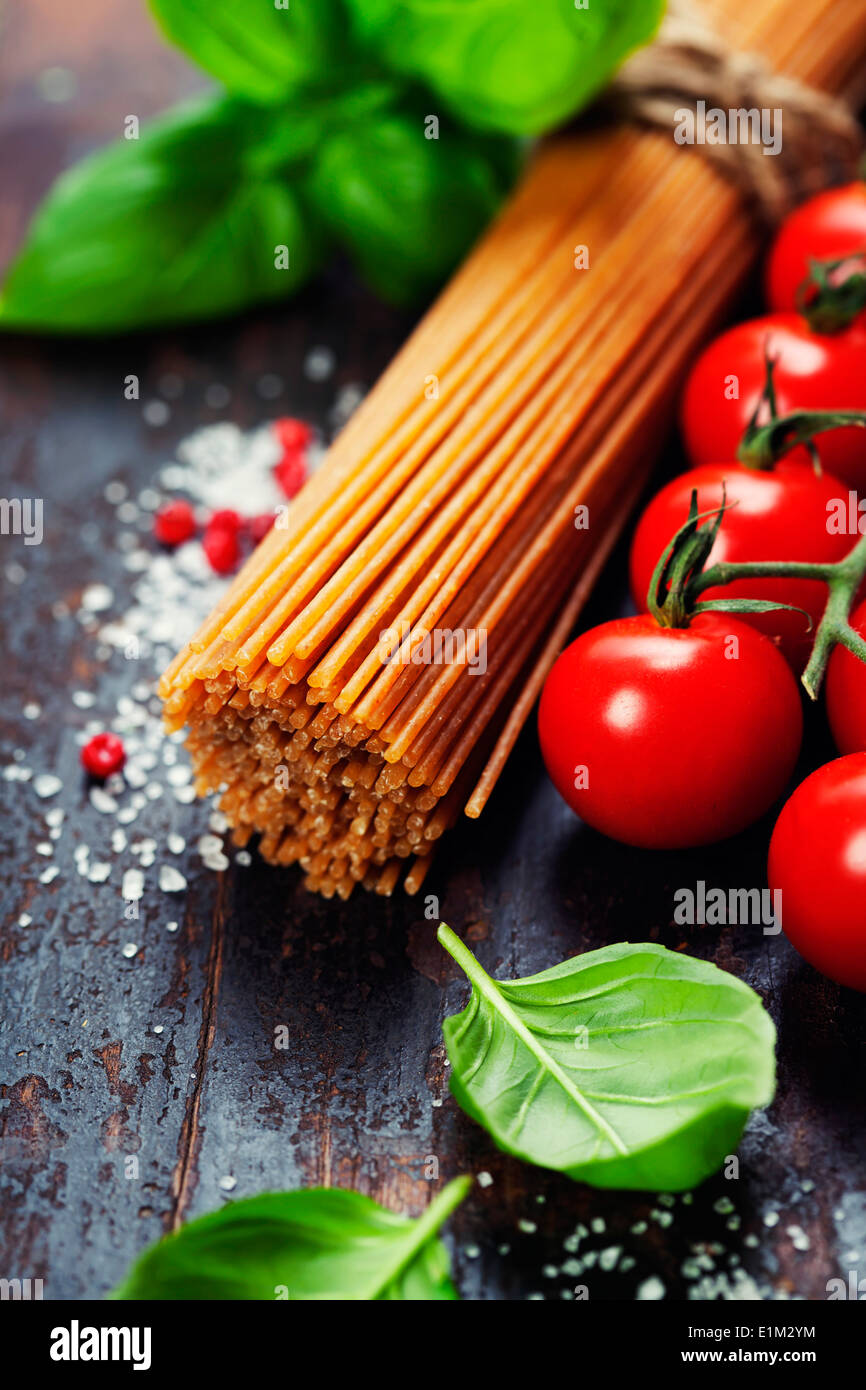 Spaghetti and tomatoes with herbs on an old and vintage wooden table Stock Photo