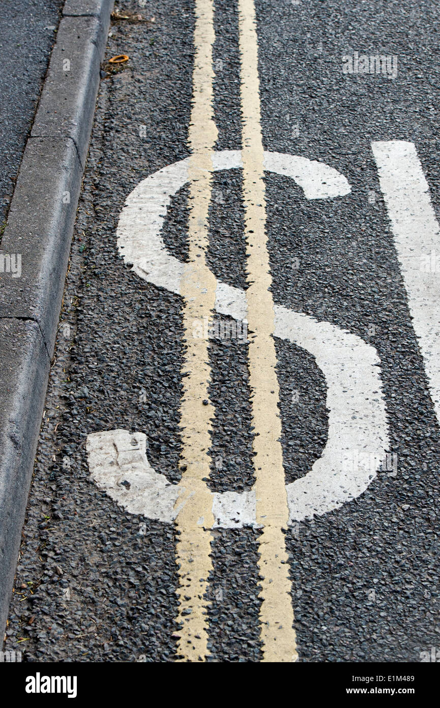 Road Marking SLOW sign painted over with double yellow line to look like a Dollar Symbol Stock Photo