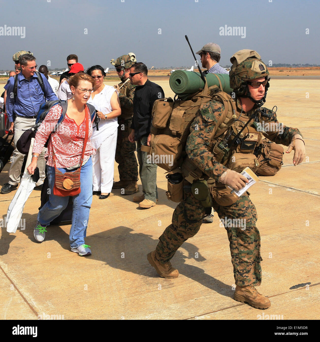 A U.S. Marine, right, assigned to Special Purpose Marine Air-Ground Task Force Crisis Response, guides U.S. citizens on a fligh Stock Photo