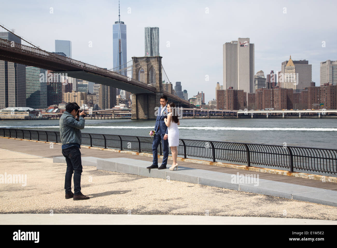 A Married Couple having their Wedding Photographs taken by Brooklyn Bridge, NYC Stock Photo