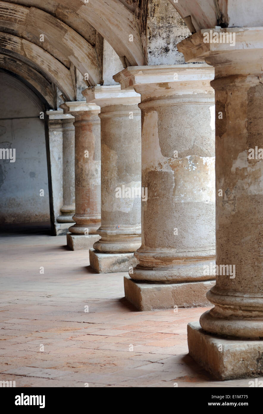 A colonnade of stout, earthquake proof pillars in the deserted Las Capuchinas convent.  Antigua Guatemala, Republic of Guatemala Stock Photo