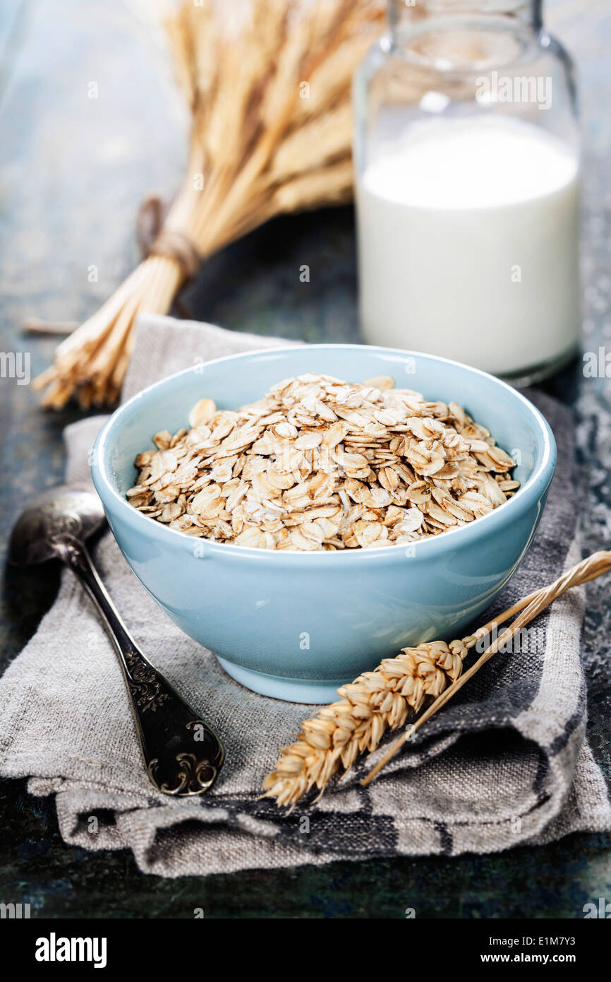 Rolled oats in a bowl and milk on wooden board Stock Photo