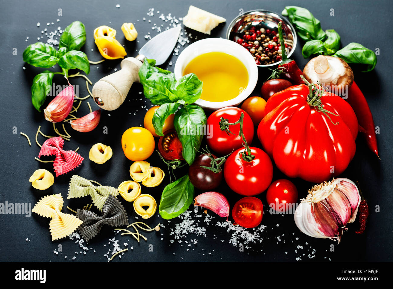 Italian ingredients pasta, vegetables, spices, cheese on dark