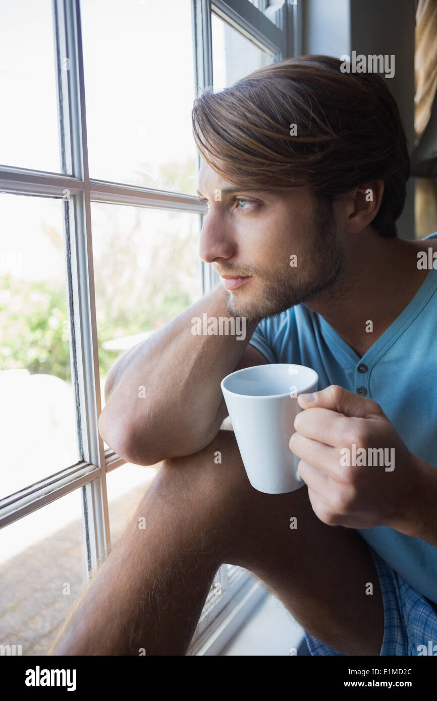 Thoughtful man sitting by the window having coffee Stock Photo