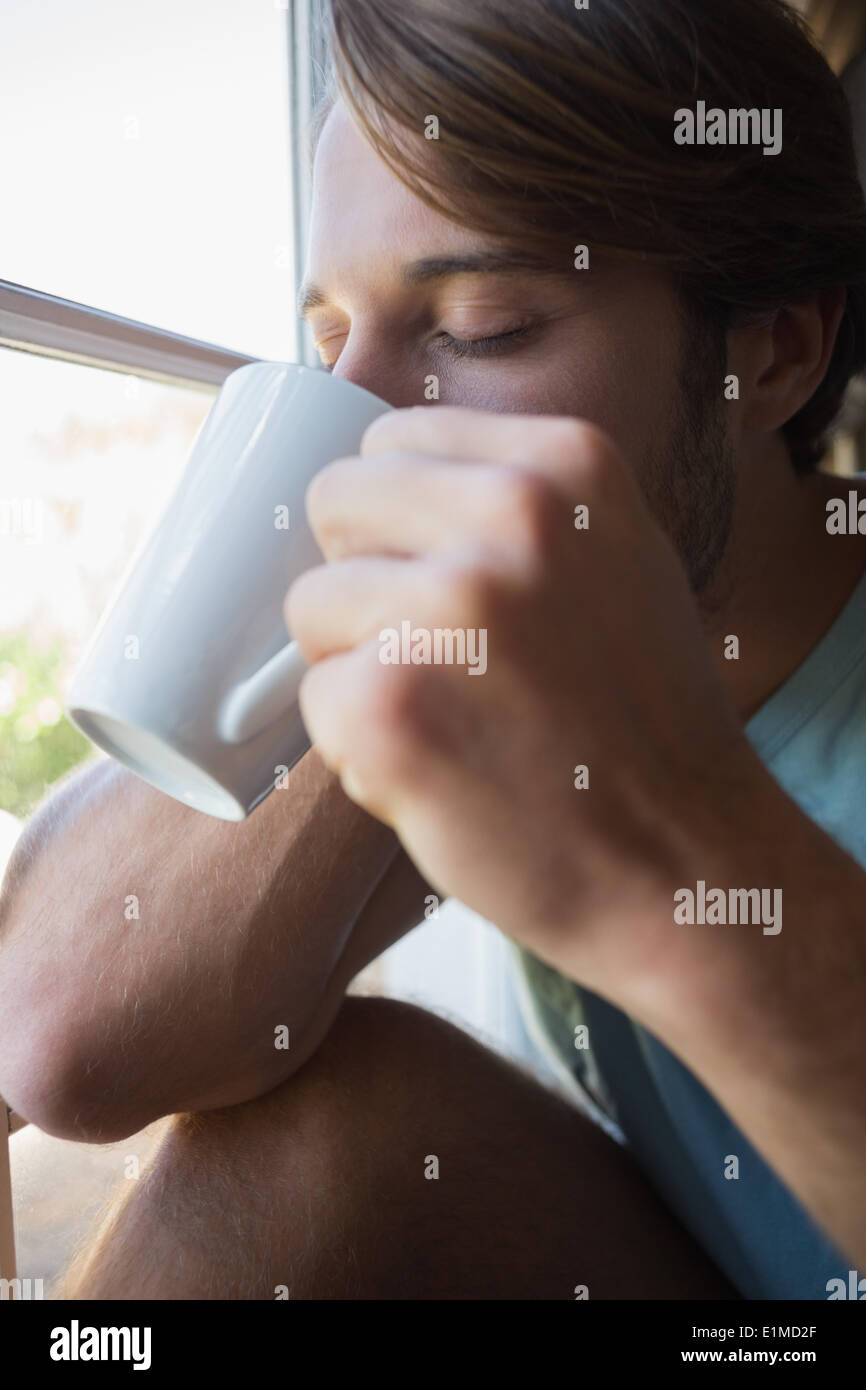 Handsome man sitting by the window having coffee Stock Photo