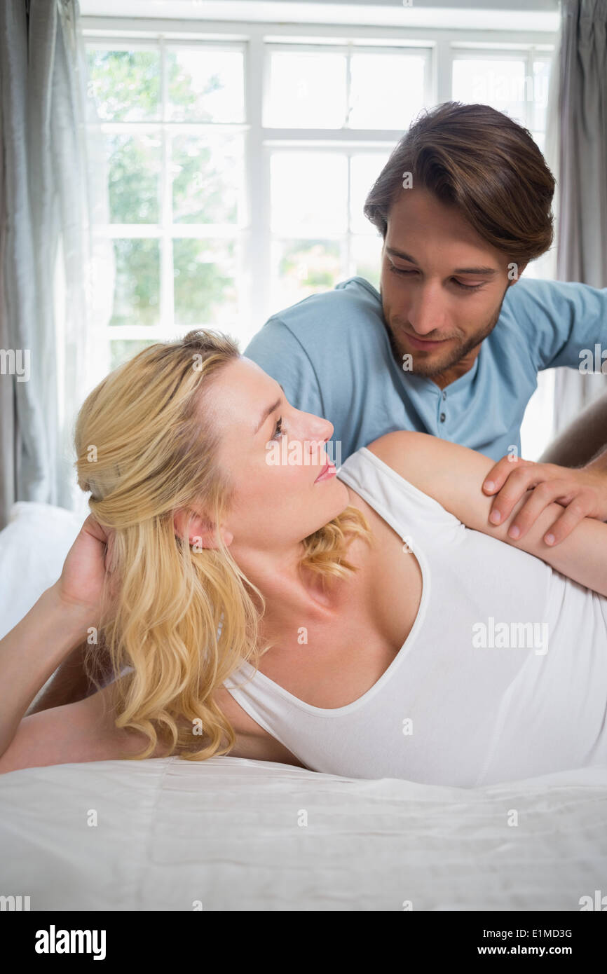 Cute couple relaxing on bed smiling at each other Stock Photo
