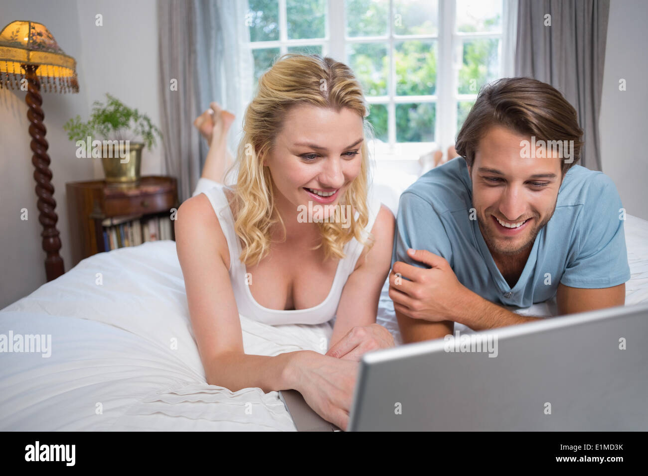 Cute couple relaxing on bed using the laptop Stock Photo