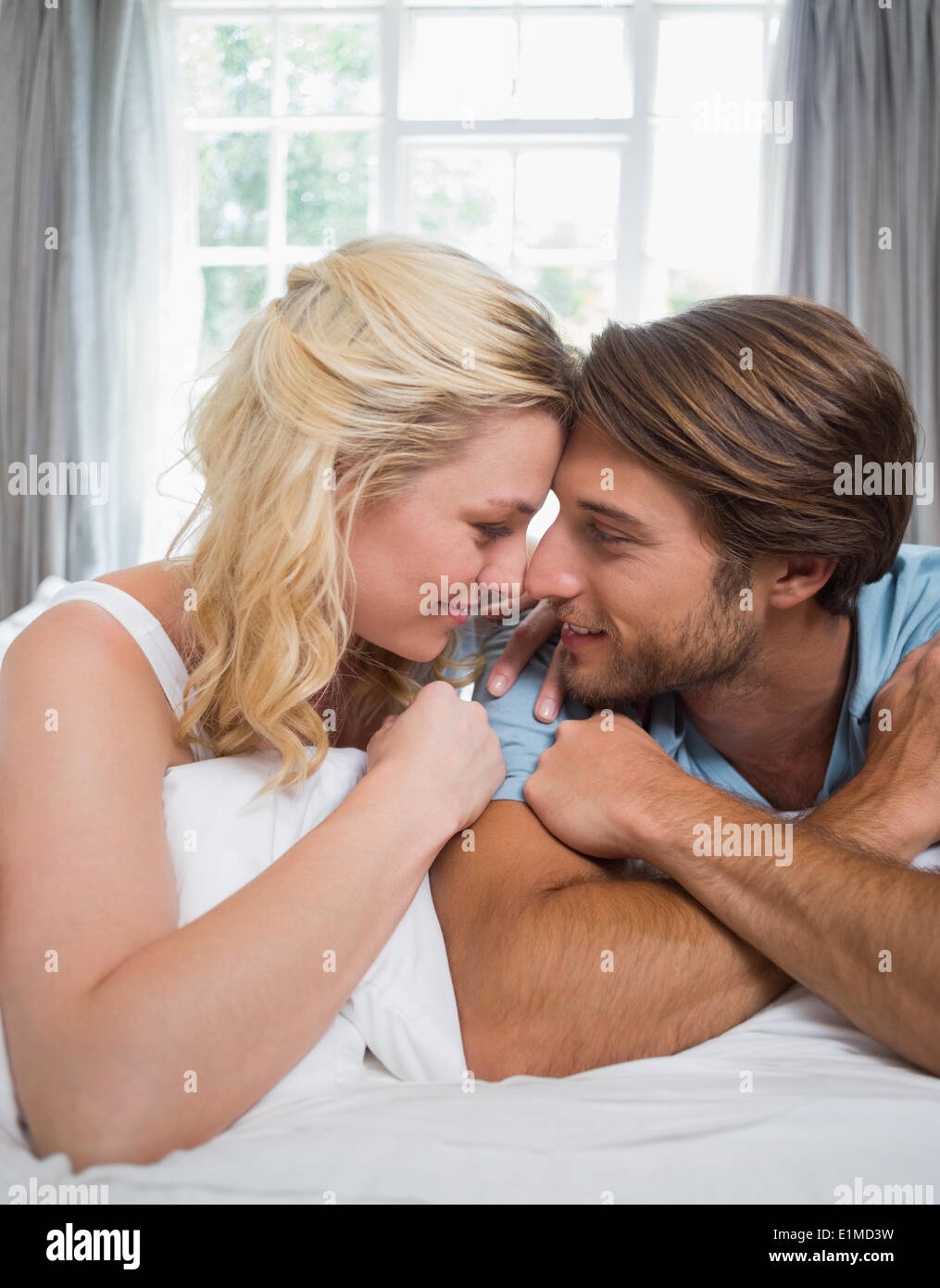 Cute couple relaxing on bed smiling at each other Stock Photo