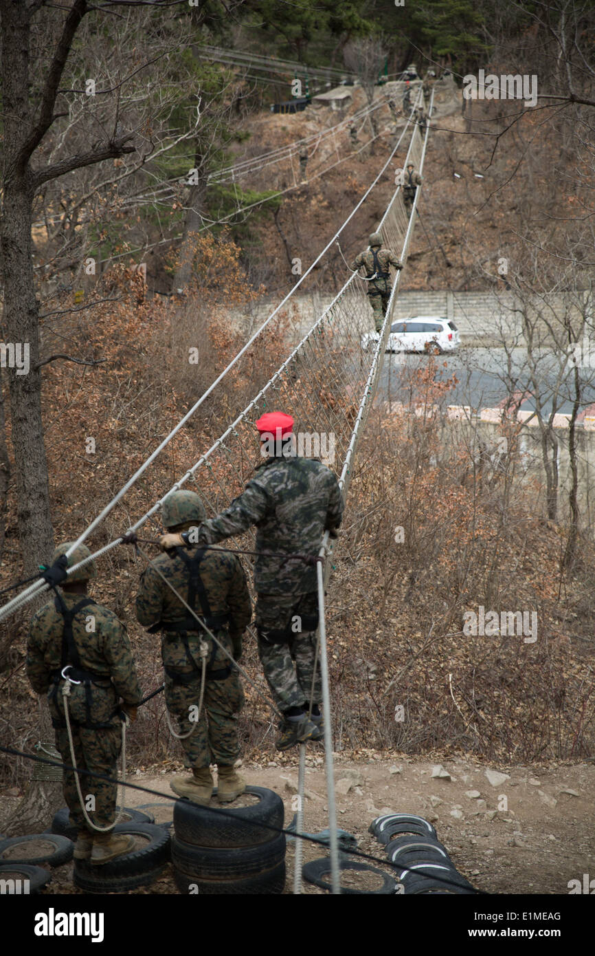 U.S. Marines with the III Marine Expeditionary Force navigate a rope bridge under the supervision of South Korean marines March Stock Photo