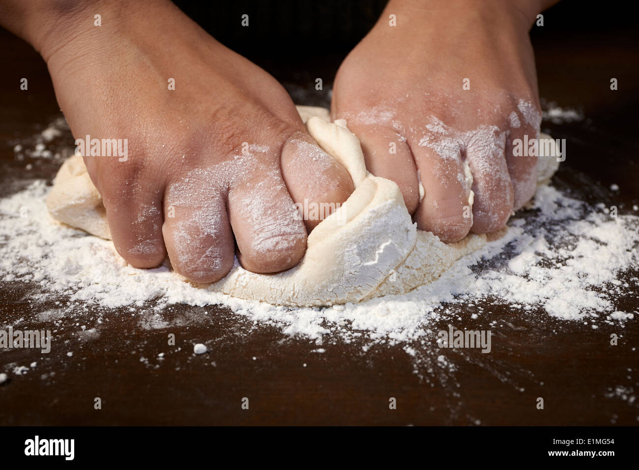 woman's hands kneading dough on wooden table Stock Photo