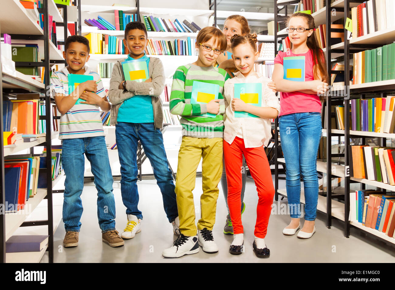 Children in library holding exercise books Stock Photo