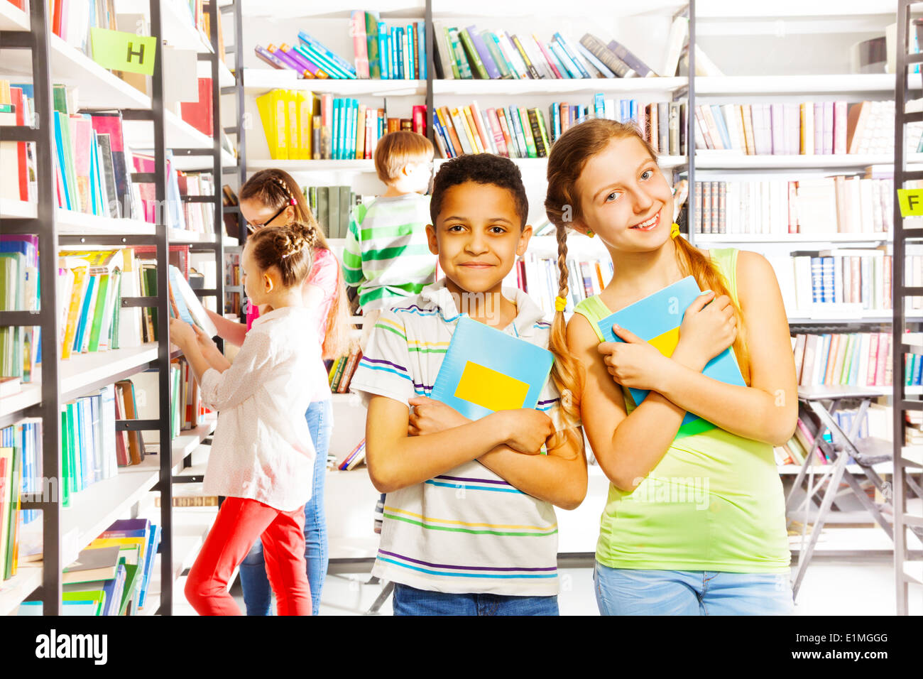 Girl and boy with books together in library Stock Photo