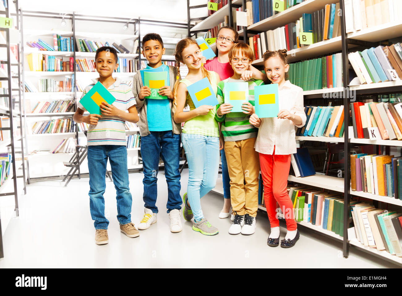 Schoolchildren with exercise books in library Stock Photo