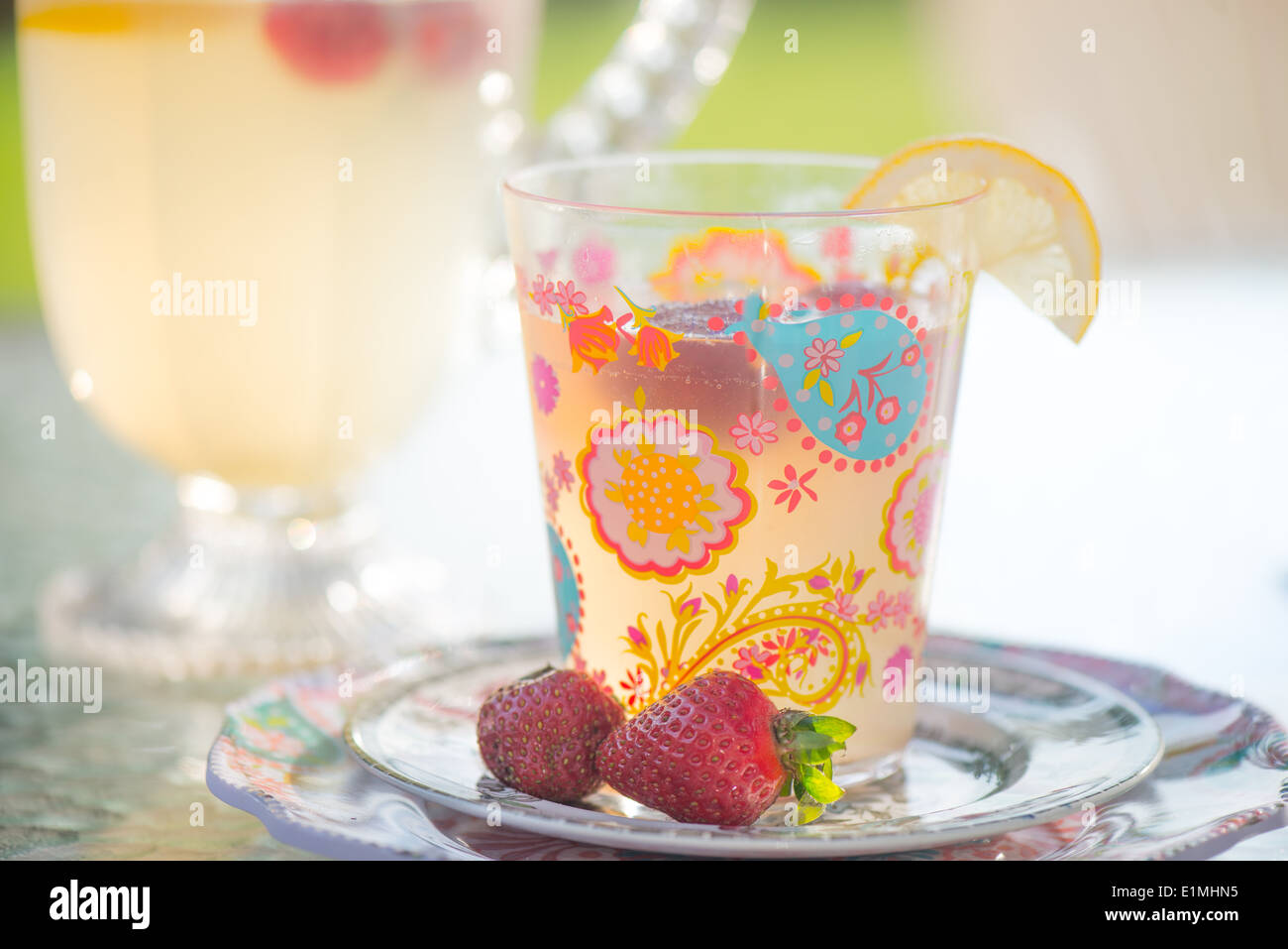 A colorful glass of lemonade with fresh strawberries as a garnish. Stock Photo
