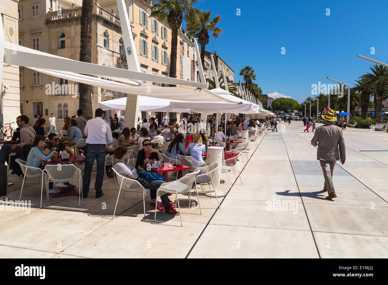 Local people and tourists walk along the Riva in split croatia. Cafes and restaurants line the side. Stock Photo