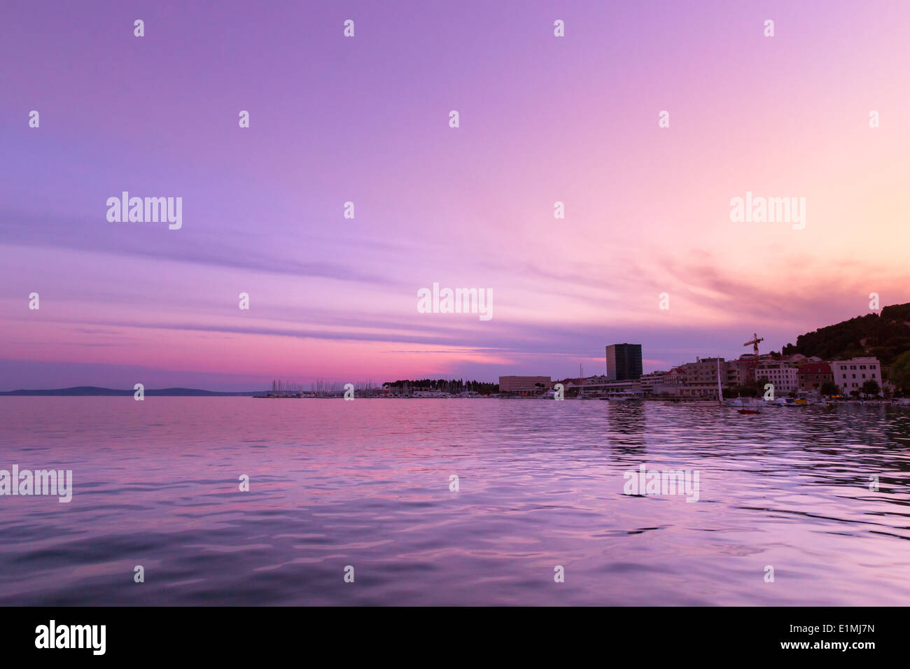 The sun creates a warm orange glow as it sets over the Marjan Hill in
